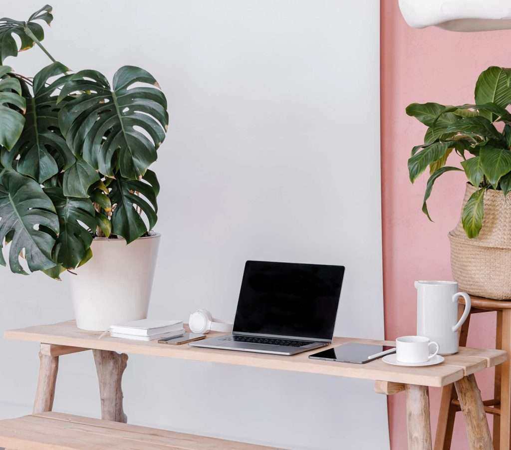 Workspace featuring a wooden desk with a laptop, notebook, and coffee cup