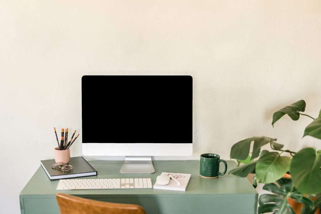 A styled green-themed workspace featuring a desk, plants, and minimalist decor, promoting productivity in an aesthetic setting.