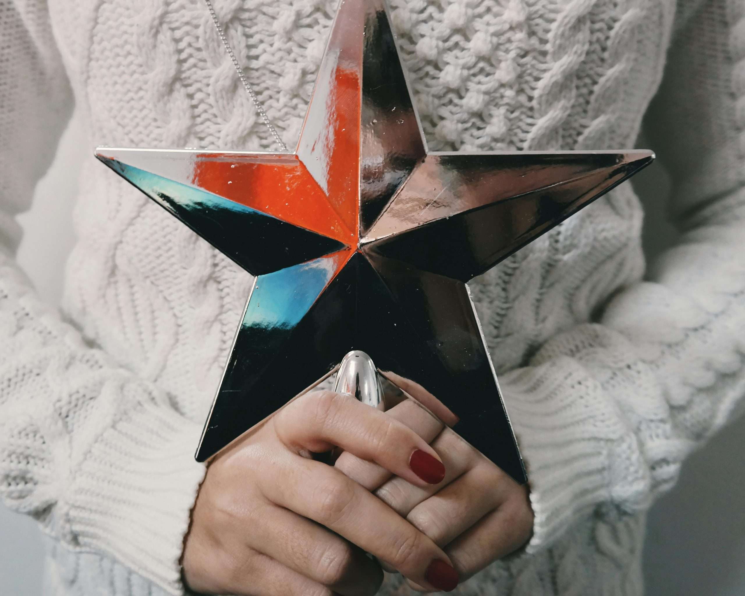 Shiny Silver Star With Red Nail Polish On Their Fingers